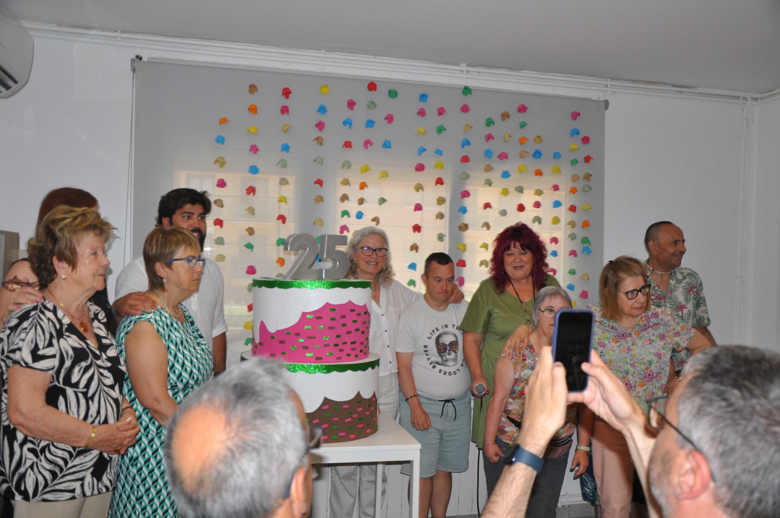 persones de llar amb el pastís de celebració dels 25 anys de la llar